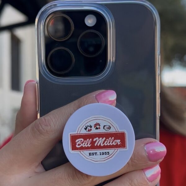 Bill Miller logo phone grip mounted on an iphone with a hand holding the phone grip.